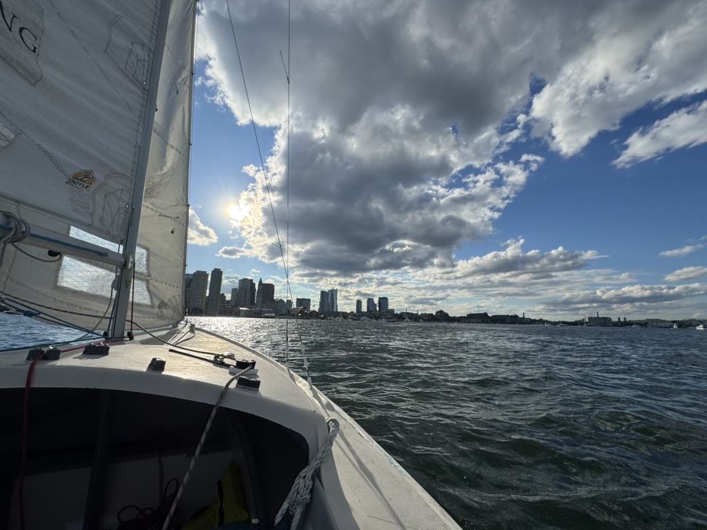 Sailboat cockpit view looking across the water toward a city skyline